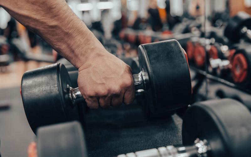 Close up shot of a hand grabbing a dumbbell in the gym.