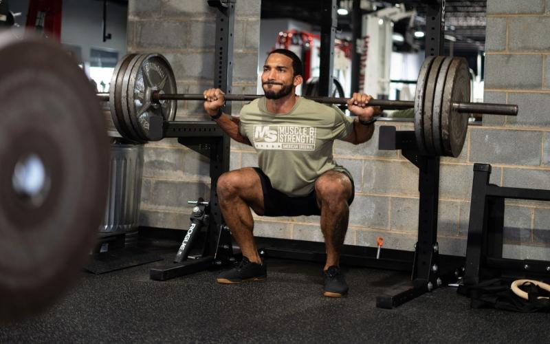 Strong male athlete doing heavy squats in the gym.